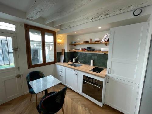 - une cuisine avec des placards blancs, une table et un réfrigérateur dans l'établissement CozyStudioParis-Montmartre-Opera, à Paris