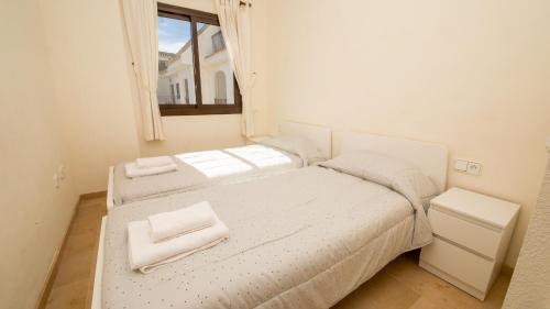 een witte slaapkamer met 2 bedden en een raam bij Marina Duquesa 544 in Manilva