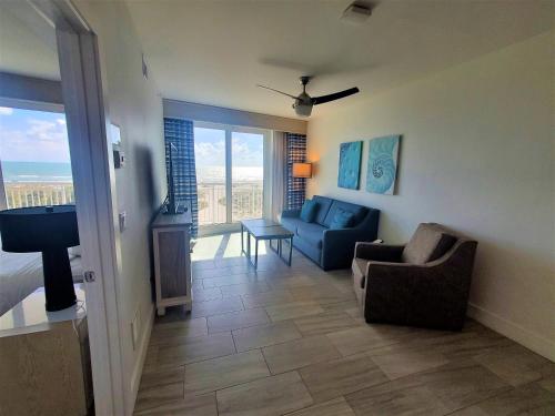 a living room with a blue couch and a chair at Provident Oceana Beachfront Suites in St Pete Beach