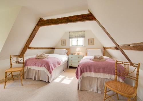 a attic bedroom with two beds and two chairs at Manor Farm in Brampton