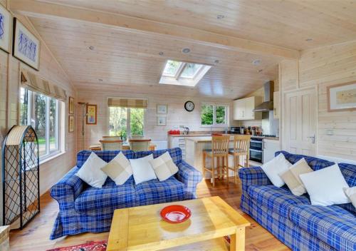 a living room with blue couches and a kitchen at Milliners Lodge in Kelling