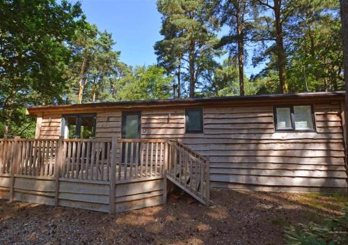 a cabin in the woods with a large deck at Milliners Lodge in Kelling