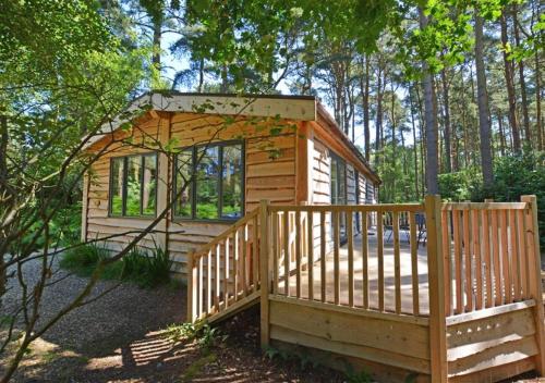 a tiny house in the woods with a wooden fence at Milliners Lodge in Kelling