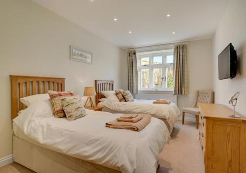 a bedroom with two beds and a desk and a tv at Mill Cottage in Elsing