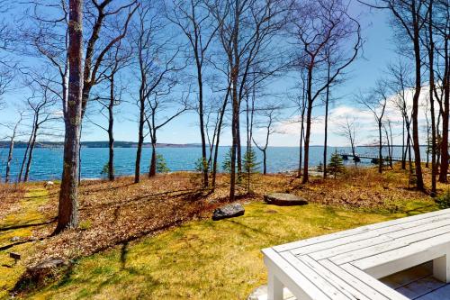 a white bench sitting on top of a field next to the water at Birds Nest in Blue Hill