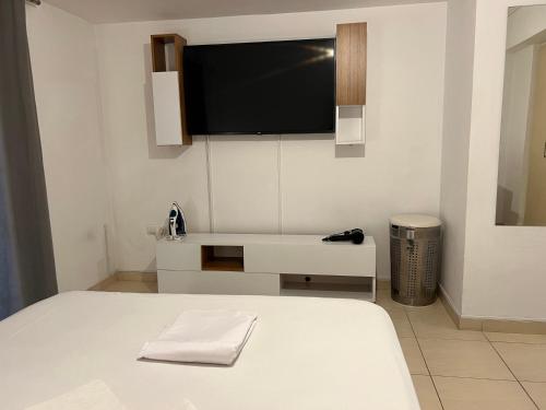 a bedroom with a bed and a tv on the wall at Jacuzzi studio close to athens airport!! in Pallíni