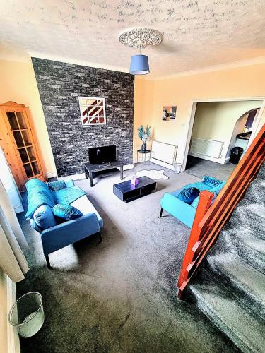 a living room with blue couches and a brick wall at Bishop Retreat in Bishop Auckland