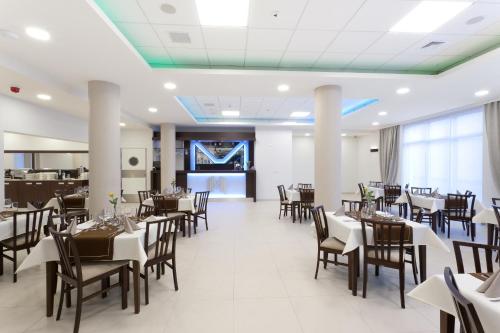 jadalnia z białymi stołami i krzesłami w obiekcie Hotel Milenium w mieście Legnica