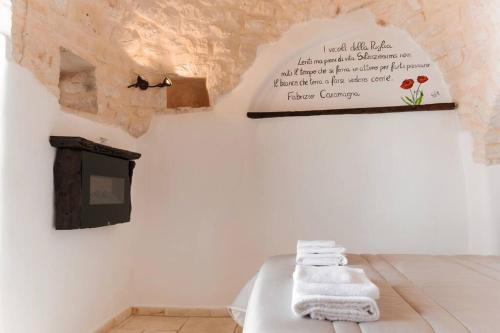 Cette chambre comprend un lit avec des serviettes et un panneau mural. dans l'établissement Il Trullo Nascosto, à Alberobello