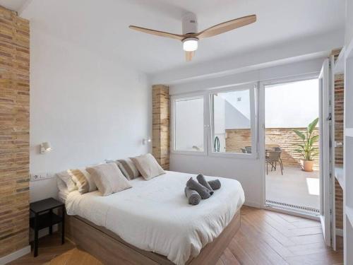 a white bedroom with a large bed and a large window at Beautiful restored house with terrace in Valencia