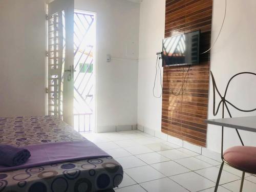 um quarto com uma cama e uma televisão na parede em La casita lilás em Beberibe