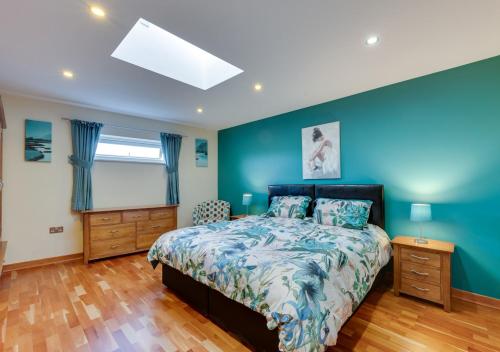 a bedroom with a bed and a blue wall at Oakdene in Great Plumstead