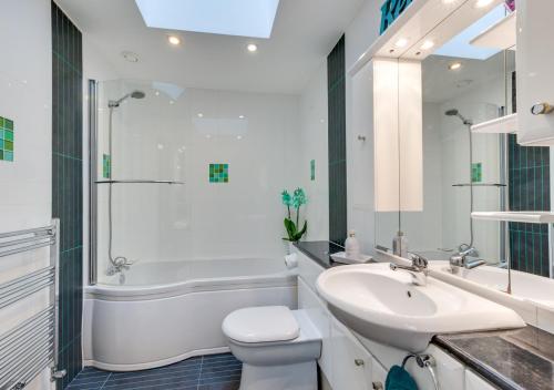 a white bathroom with a sink and a toilet and a tub at Oakdene in Great Plumstead