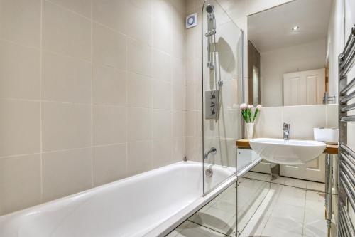 a bathroom with a white tub and a sink at Stunning Award Winning Barn Conversion- 2 Bedroom in London