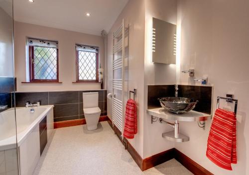 a bathroom with a sink and a toilet and a tub at Nursery Cottage in Clippesby