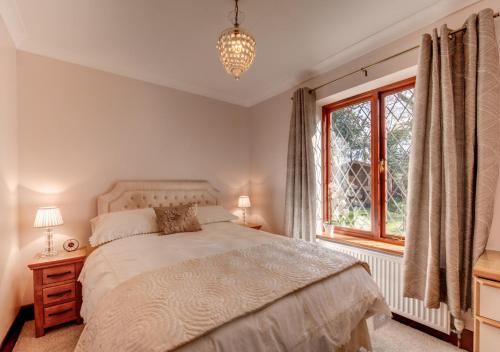 a bedroom with a bed and a window at Nursery Cottage in Clippesby