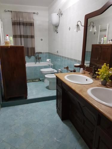 een badkamer met 2 wastafels, een toilet en een spiegel bij Just Pompei Holiday House in Scafati