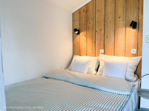 um quarto com uma cama e uma cabeceira em madeira em FeWo Frieda's Platz am Meer em Dangast