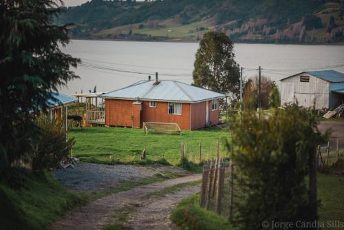 a house on a field next to a body of water at Cabañas Reflejo de Luna in Castro