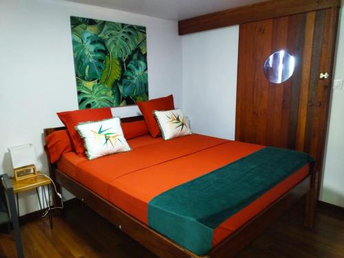 a bedroom with a bed with an orange and green comforter at LE CHALET DOMAINE DU ROCHER in Bourda