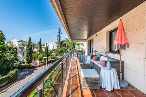 a balcony with a couch and an umbrella at Apartamento Marbella Center III in Marbella