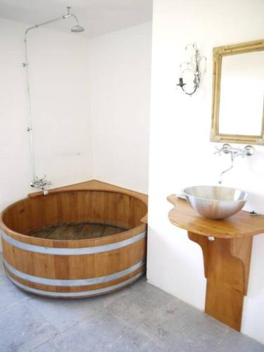 La salle de bains est pourvue d'une baignoire en bois et d'un lavabo. dans l'établissement Location gîtes château Couronneau, à Ligueux