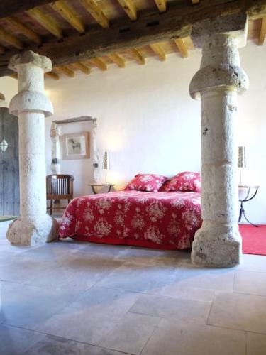 une chambre avec un lit rouge à deux colonnes dans l'établissement Location gîtes château Couronneau, à Ligueux