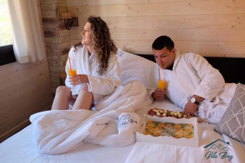 un hombre y una mujer sentados en una cama con bebidas en Vila Breg Zlatibor, en Zlatibor