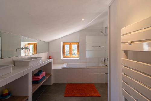 La salle de bains blanche est pourvue d'une baignoire et d'un lavabo. dans l'établissement Les Bergeries de Figari, à Figari