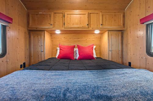 Cama en habitación de madera con 2 almohadas rojas en JT Village Campground - Sun Ray, en Joshua Tree
