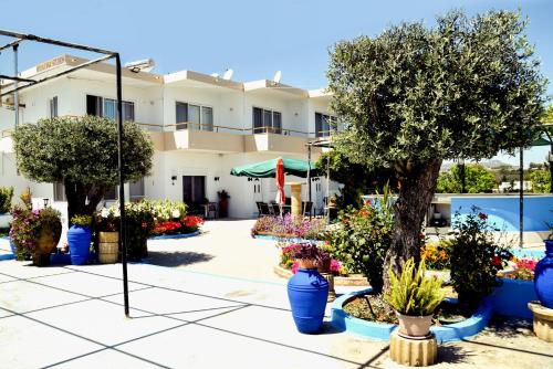 a garden in front of a building with blue vases of flowers at BELLA CASA KOLYMPIA in Kolymbia