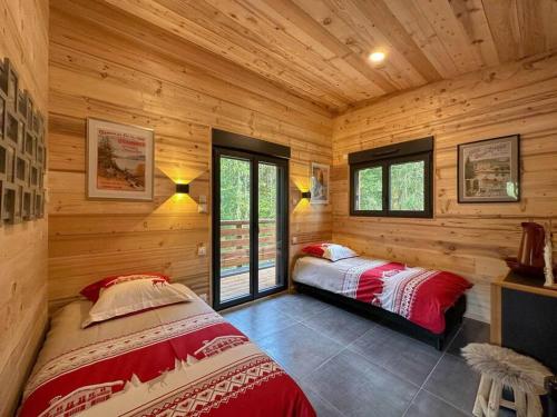 two beds in a room with wooden walls and windows at Le Refuge perché du saut de la bourrique SPA, terrain clôturé Gérardmer in Gérardmer