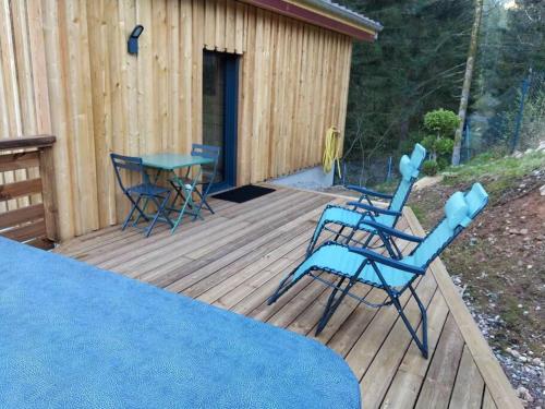 two blue chairs and a table on a wooden deck at Le Refuge perché du saut de la bourrique SPA, terrain clôturé Gérardmer in Gérardmer