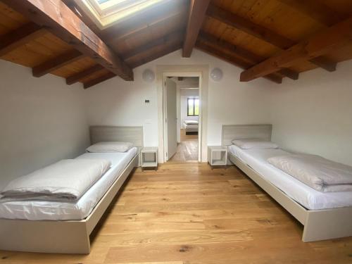 two beds in a room with wooden floors at Vera Park & Wellness in Belluno