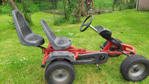 a four wheeler with two seats sitting in the grass at Holiday Home Achterbos in Sint-Oedenrode