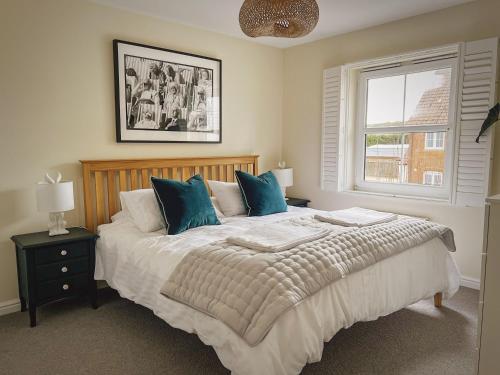 a bedroom with a bed with blue pillows and a window at Whitebeam in Camber