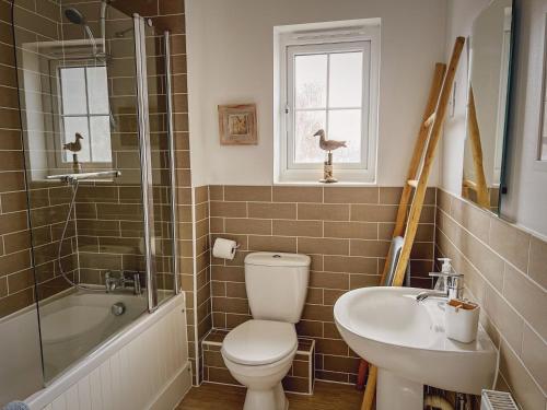 a bathroom with a toilet and a sink and a tub at Whitebeam in Camber