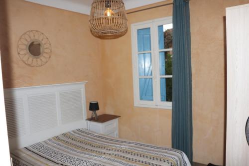 - une chambre avec un lit, une fenêtre et un lustre dans l'établissement Maison bord de mer, à Saint Cyprien Plage