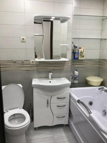 a bathroom with a toilet and a sink and a tub at Apartment near the seaside in Batumi