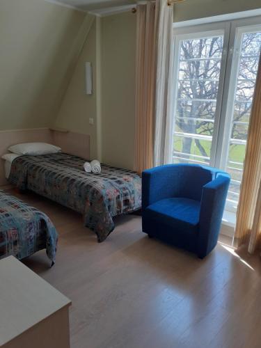 a bedroom with a blue chair and a bed and a window at Inge Villa in Pärnu