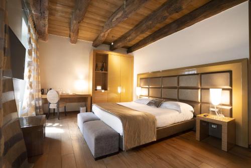una camera con un grande letto, una scrivania e una sedia di Il Borgo - 1711 Luxury Guest House ad Arlate