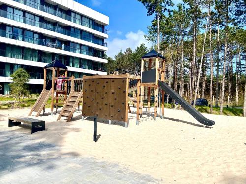 a playground in the sand in front of a building at Rogowo Prestige Shellter in Rogowo