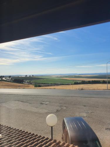 una ventana con vistas a la carretera y una maleta en Hostal Carlos III en Aldea Quintana