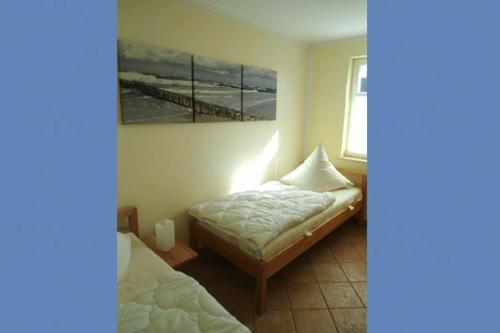 a bedroom with two beds and a painting on the wall at Am Park, App Dünennest in Wustrow