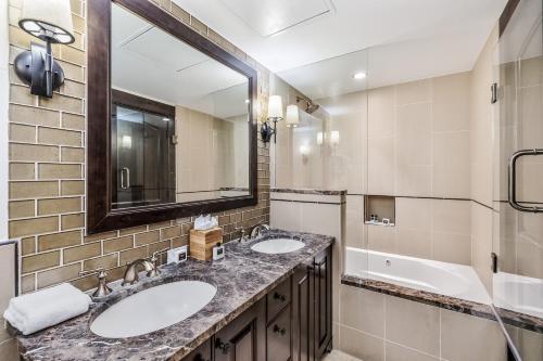 a bathroom with two sinks and a mirror and a tub at Spacious Luxury Unit at Lionshead Village in Vail in Vail