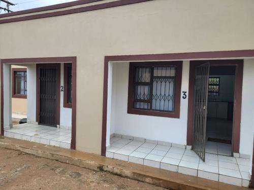 a white building with three doors on it at Mavundla lifestyle lodge in Empangeni
