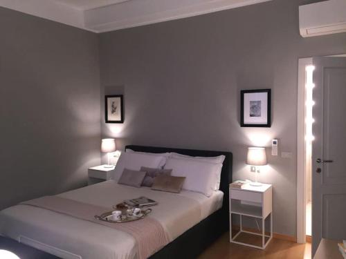 1 dormitorio con 1 cama con 2 mesas y 2 lámparas en Repubblica90 eleganza e confort, en Parma