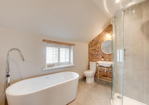 a bathroom with a tub and a toilet and a sink at Peacock Cottage in Holt
