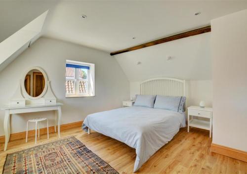 ein weißes Schlafzimmer mit einem Bett und einem Spiegel in der Unterkunft Rose Cottage in Stiffkey