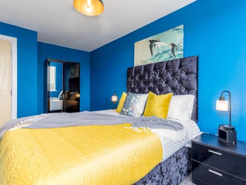 um quarto azul com uma cama king-size e almofadas amarelas em Pass the Keys Central One bed apartment em Nottingham